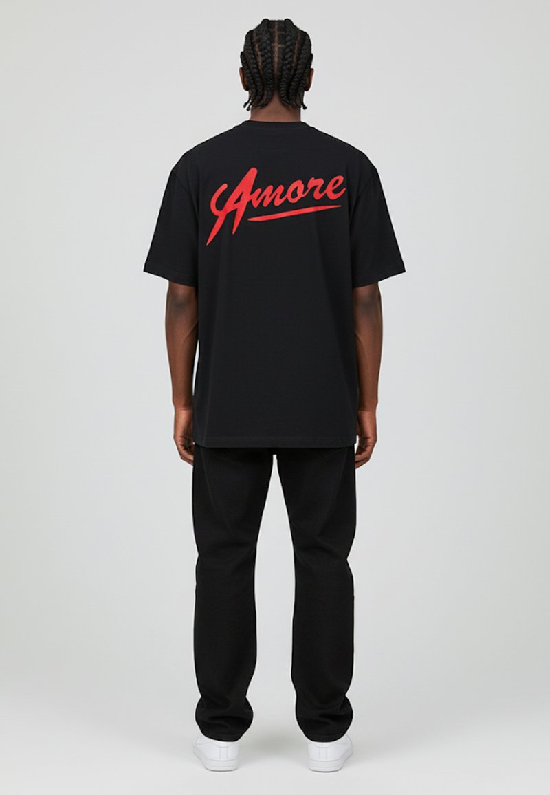 Camiseta negra de manga corta con "Amore" impreso en rojo en la parte de atrás. Lleva pantalones negros y zapatillas blancas. Diseño simple y casual.