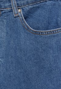 Tissu en denim bleu avec une poche avant, une boucle de ceinture et un rivet métallique montrant une couture orange sur un jean.