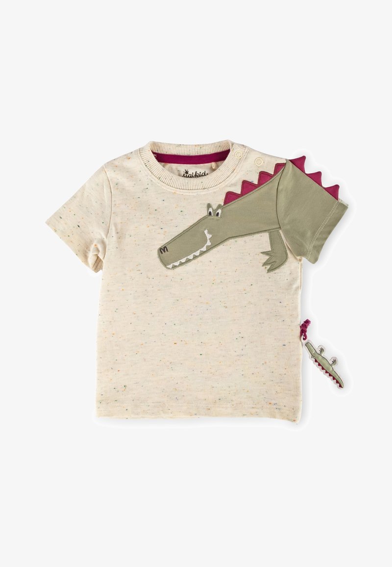 T-shirt crème pour tout-petit avec un motif de crocodile vert, des pointes violettes sur la manche et une tirette assortie suspendue sur le côté.