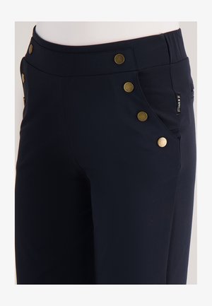 Marineblauwe broek met een aansluitend ontwerp, voorzien van vijf gouden knopen langs de taille en zijzakken. Gemaakt van een gladde, rekbare stof.