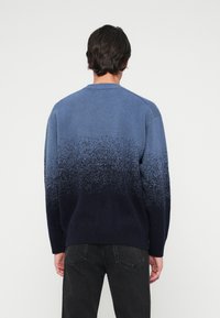 Sweater em tecido de malha com gradiente azul, passando de azul claro a azul marinho escuro, apresentando punhos e barra canelados, com decote redondo.