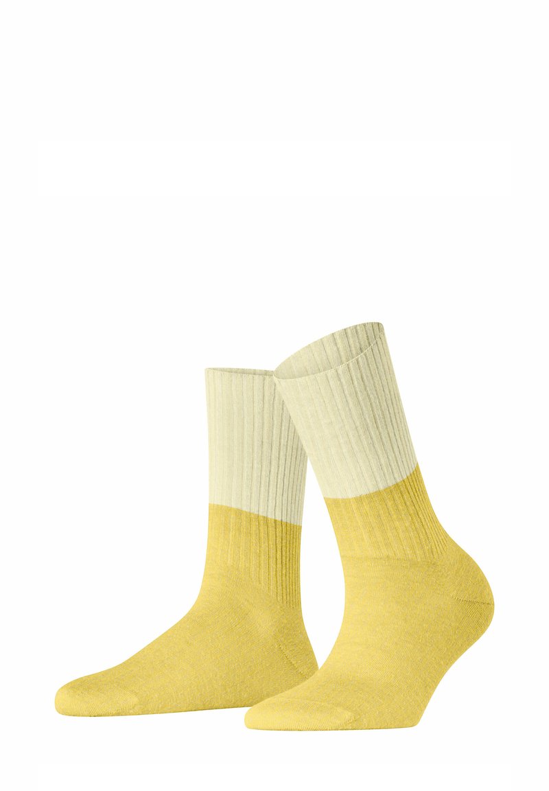 Gelbe Socken mit einem gerippten Design. Sie verfügen über einen cremefarbenen oberen Abschnitt und einen einfarbig gelben unteren Abschnitt. Hergestellt aus einem weichen, strukturierten Stoff.