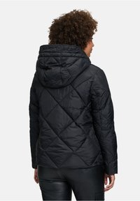 Sort dunjakke med en quiltet diamantmønster, der har en hætte og lange ærmer. Materialet ser glat og let ud.