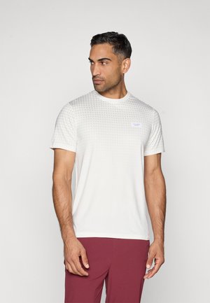 Vit T-shirt med kort ärm och strukturerat prickigt mönster, rund hals, och liten logotyp. Kombineras med vinröda träningsshorts.