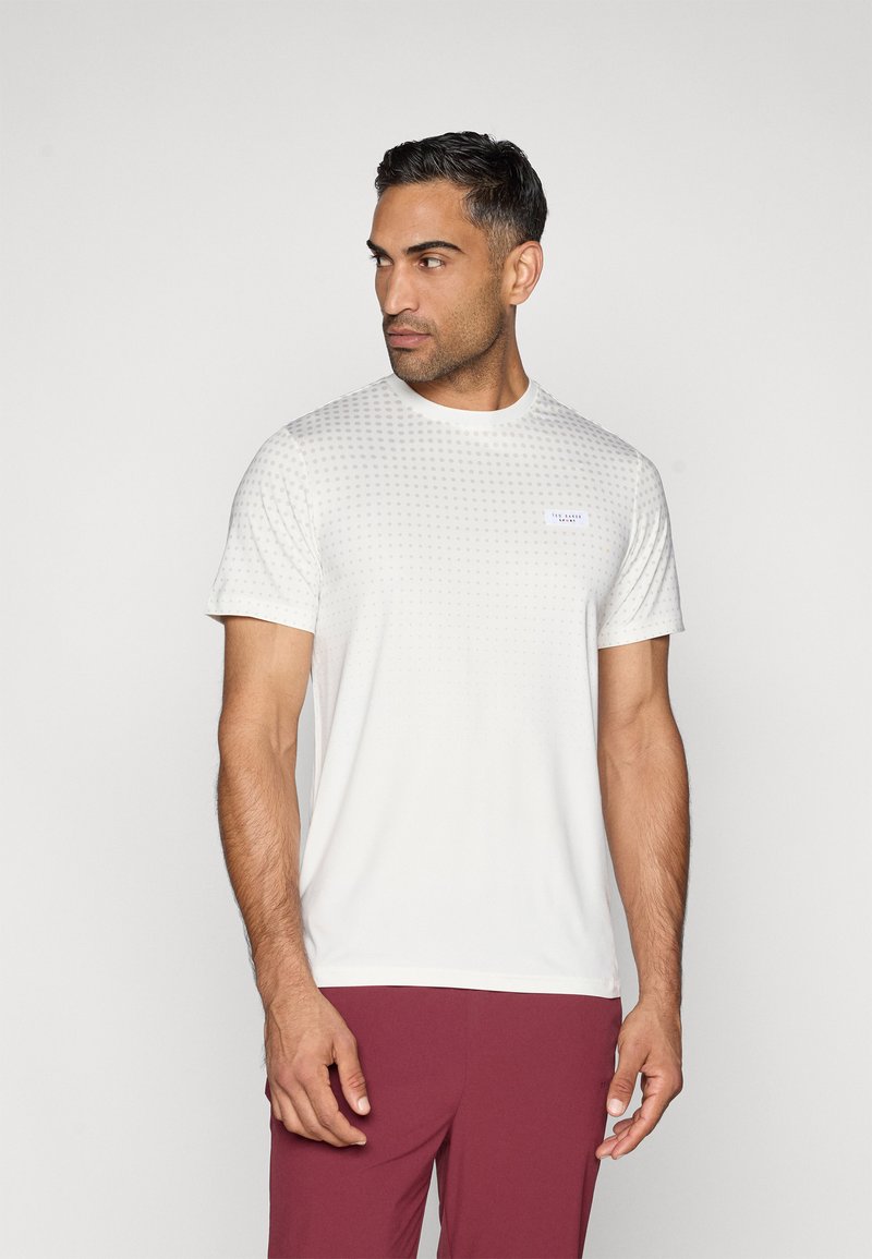 Balts īss piedurkņu T-krekls ar tekstūru punktētu rakstu, apaļu kakla izgriezumu un mazu logo uzšuvumu. Apvienots ar tumši sarkaniem sporta šortiem.