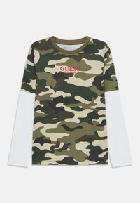 Camouflierter Langarmshirt mit olivgrünen, schwarzen und beigen Mustern. Verfügt über einen Rundhalsausschnitt, weiße Ärmel und roten Text "GUESS EST 1981" auf der Vorderseite.