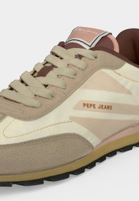 Κοντινό πλάνο ενός μπεζ και κρεμ sneaker Pepe Jeans με μπεζ κορδόνια και καφέ λεπτομέρειες στη σόλα και το εσωτερικό επένδυμα.