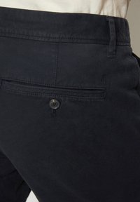 Pantaloni in misto cotone blu navy con fronte piatto, una tasca posteriore singola e chiusura con bottone, caratterizzati da un discreto dettaglio del logo.