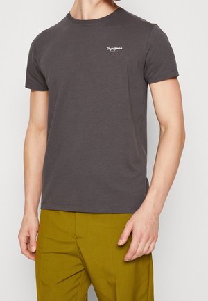 Dunkelgraues T-Shirt mit kurzen Ärmeln aus Baumwolle, mit Rundhalsausschnitt und einem kleinen weißen Logo auf der Brust. Kombiniert mit olivgrünen Hosen.