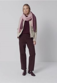 Beige jakke over en maroon sweater, brune bukser og et lyserødt tørklæde. Bukserne har lige snit; tørklædet har et tekstureret design. Brune støvler fuldender outfittet.