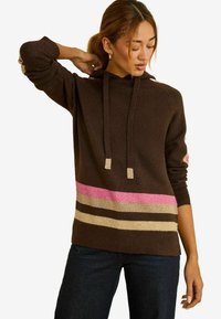 Rudas gobtuvuotas megztinis su rožinėmis, kremine ir tamsiai rudos spalvos juostelėmis. Turi laisvą siluetą ir pasagintas rankogalius. Minkšta tekstūra, laisvalaikio dizainas.