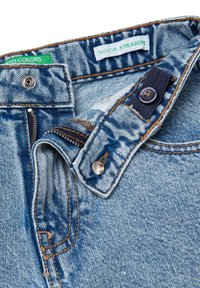 Vaqueros de denim de color azul claro con corte recto, que presentan un cierre de cremallera, botón de metal y costuras en naranja a contraste. Incluye etiquetas.