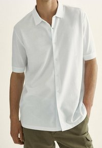 Weißes kurzärmliges Hemd aus glattem Stoff mit Knopfleiste vorne und klassischem Kragen. Es hat eine lockere Passform und keine sichtbaren Muster.