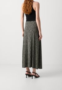 Jupe maxi en tissu léger, avec un motif abstrait noir et beige, dotée d'une coupe évasée et d'une longueur aux chevilles.