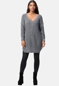Abito maglione grigio a collo a V, maniche lunghe e motivo testurizzato. Abbinato a jeans skinny neri e stivaletti.