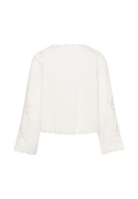 Blouse blanche à manches longues avec bords festonnés et détails brodés de découpes florales sur les manches et l'ourlet.