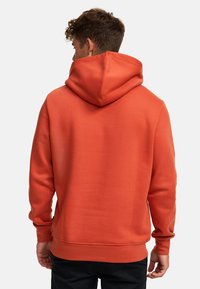 Felpa da uomo in arancione pieno, realizzata in tessuto morbido. Presenta un grande cappuccio, maniche lunghe e polsini e orlo a coste. Texture liscia e uniforme.