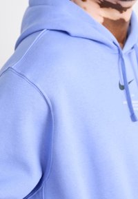 Lavender hoodie made of soft fabric, featuring a front pocket, drawstring hood, and printed logo in black on the chest for contrast.