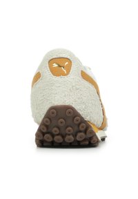 Sneaker crema e marrone chiaro con tomaia testurizzata, lacci rotondi e suola in gomma marrone con tacchetti circolari per la trazione. Dettaglio decorativo in oro.