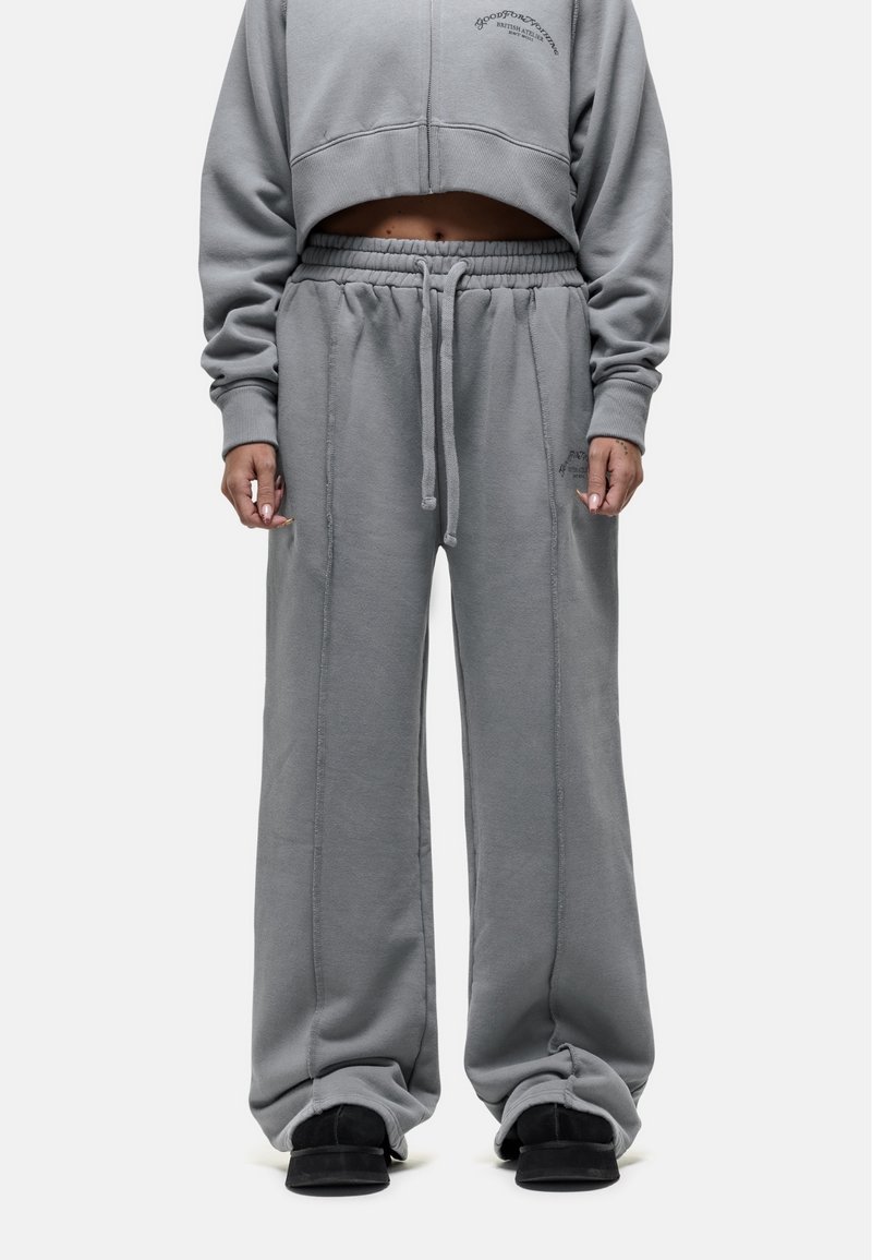 Jasnoszara krótkowana bluza z długim rękawem oraz pasujące szerokie spodnie dresowe z miękkiego materiału, z elastycznym pasem i sznurkiem. Widoczne szczegóły przeszyć.