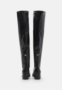 Botas negras hasta la rodilla, hechas de cuero suave, con un tacón cuadrado y cremalleras laterales. Diseño simple con un acabado brillante y sin patrones visibles.