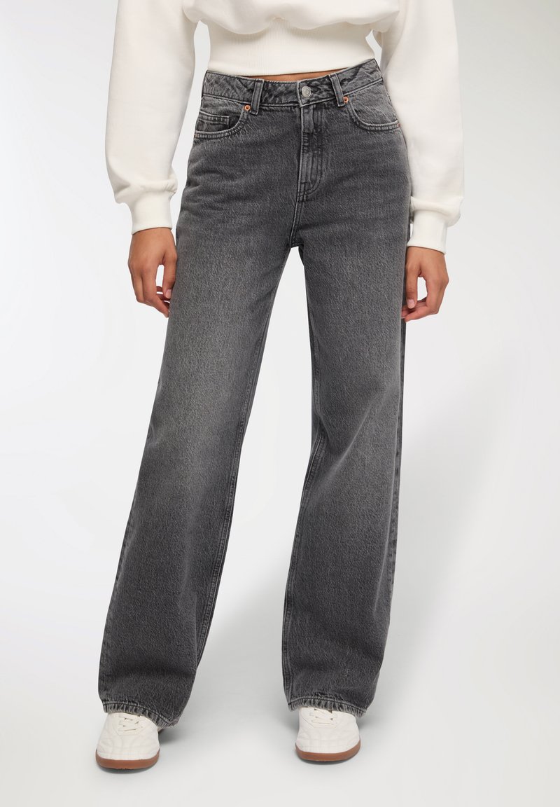 Jeans a vita alta e gamba ampia in denim nero sbiadito, con un classico design a cinque tasche e cuciture a vista.