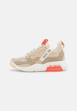 Zapatilla deportiva beige y marrón claro con suela blanca, amortiguación de aire naranja, cordones azul claro y lengüeta roja sobre un fondo blanco.