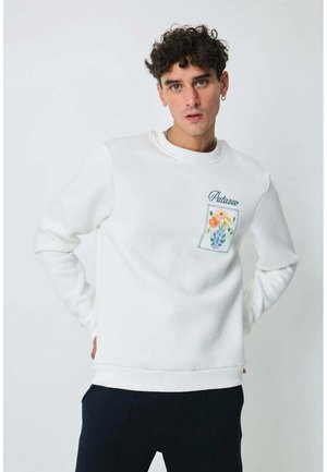 Sweatshirt blanc avec col rond, ornée d'une broderie florale sur une poche et de détails cousus. Texture douce et coupe décontractée.