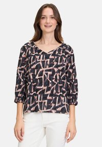 Blusa nera e rosa con motivo a V, maniche a tre quarti e vestibilità comoda, caratterizzata da forme astratte su uno sfondo chiaro.