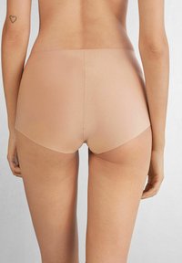 Naadloos hoge taille slipjes in een licht nude kleur, met een gladde, zachte textuur en minimale stiksels voor een comfortabele pasvorm.