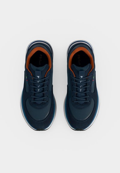 Paire de baskets bleu marine à lacets avec doublure intérieure orange et semelles blanches vues de dessus sur fond blanc.