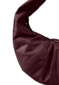 Sac hobo en cuir bordeaux avec texture lisse, design froncé et accent de fermeture éclair dorée ; présente des détails cousus le long des coutures.