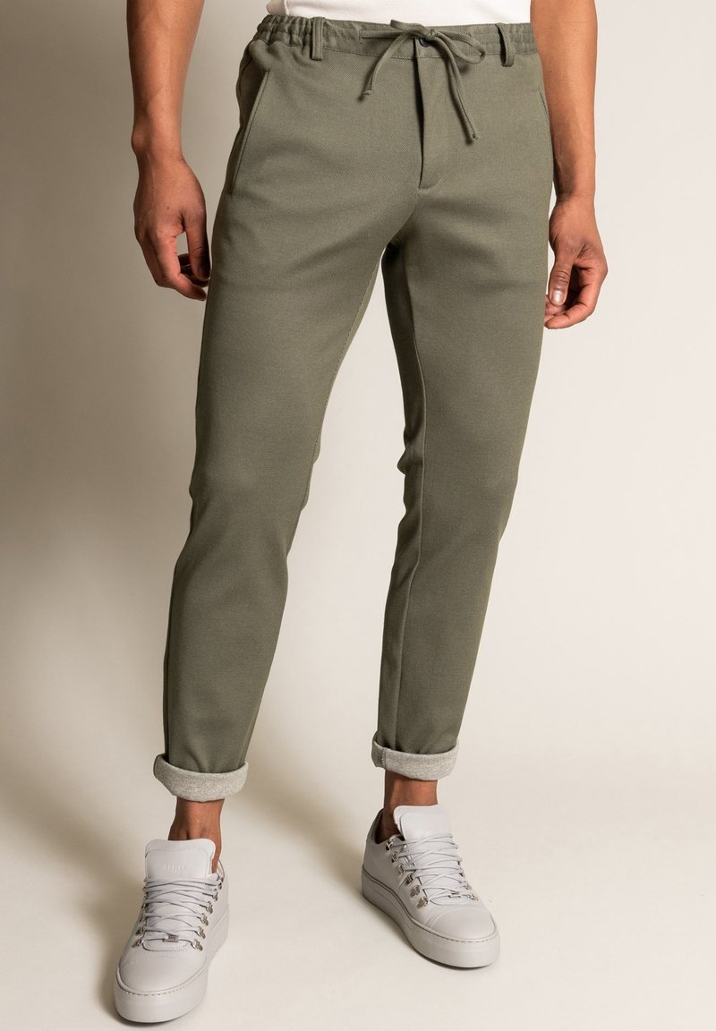 Olive green joggers with a tapered fit, elastic waistband, and adjustable drawstring. Features cuffed hems and side pockets.