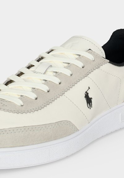 Pantof sneaker alb și gri cu talpă texturată, șireturi albe și logo negru cu jucător de polo pe lateral.