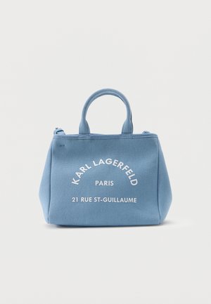 Sac à main en tissu bleu clair avec deux poignées, portant le texte blanc "Karl Lagerfeld Paris 21 Rue St-Guillaume" sur le devant.