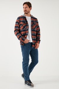 Rød og marineblå ternet flannel skjorte med to brystlommer, grå hætte, båret over en hvid t-shirt. Sammen med blå jeans og sneakers.