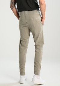 Hellgraue Jogginghose im tapered Fit, mit elastischem Bund und gerippten Bündchen. Verfügt über eine Gesäßtasche und eine weiche Stoffoberfläche.
