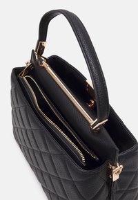 Zwarte gewatteerde handtas van getextureerd leer, met goudkleurige hardware en een ritssluiting. Bovenhandgreep voor eenvoudig dragen.