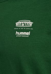 Green sweatshirt featuring a white graphic with an architectural design and text: "serving the game for generations," and "hummel sportswear."