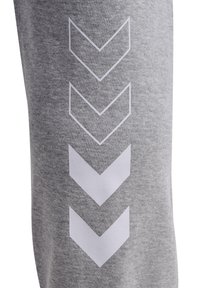 Grau gestreifte Jogginghosen mit fünf weißen Chevron-Formen, die vertikal entlang der Seite verlaufen und ein schlichtes sowie sportliches Design unterstreichen.