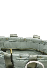 Opgevulde groene boodschappentas met twee stoffen handvatten, een ritscompartiment en gouden Hardware. Zachte textuur, met een zichtbaar binnenvoering.