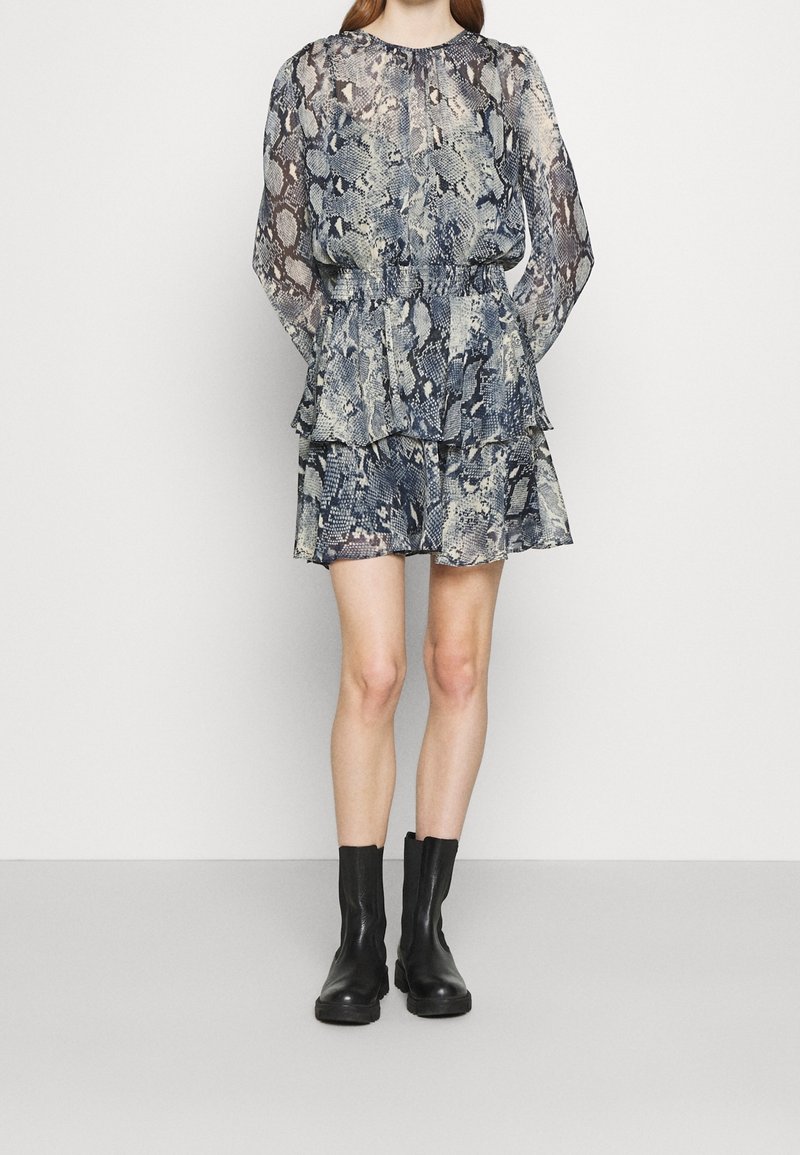 Vrstvené šaty s dlouhým rukávem a modro-krémovým hadím potiskem. Vyrobené z lehkého materiálu, mají vypasovaný pas a rozšířenou sukni.