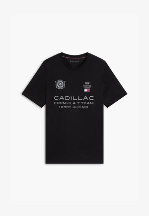 Svart T-skjorte med korte ermer med Cadillac Formula 1 Team- og Tommy Hilfiger-logoer, med racinginspirerte merker på brystet.