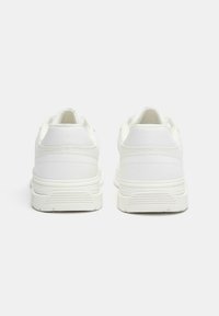 Weiße Sneaker mit einem glatten Stoff-Außenschuh, strukturiertem Fersenbereich und strukturiertem Gummi-Außensohlenmaterial. Minimalistisches Design ohne sichtbare Markenkennzeichnung.