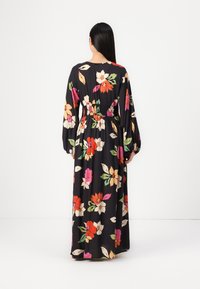 Maxikjole med lange ærmer, laget av lett stoff. Har en svart bakgrunn med fargerike blomster mønstre, samlet midje, og flytende silhuett.
