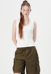 Hvitt ribbet tank topp med rund hals, kombinert med olivengrønne cargo shorts med sidelommer og elastisk midje.