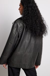 Schwarze Lederjacke mit lockerer Passform, breiten Revers, sichtbaren Nähten und einer glatten Textur. Sie hat einen geraden Saum und lange Ärmel.