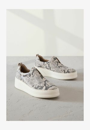 Slip-on sneakers met een textuur van een slangprint in zwart en wit. Voorzien van een witte plateauzool en elastische zijkanten.