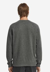 Grauer Strickpullover mit geripptem Saum und Bündchen, Rundhalsausschnitt und struktuierter Oberflächenbeschaffenheit, von hinten betrachtet.