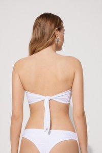 Bílé bandeau bikini z texturované látky, s designem s uvázáním na zádech a odpovídajícími spodními díly. Má hladkou, přiléhavou siluetu se subtilními vzory.